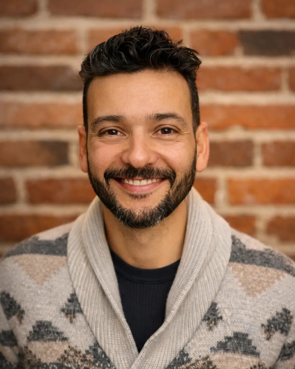 Portrait of Jorge Vasquez, principal of Vasquez Design Studio, smiling in front of a brick wall